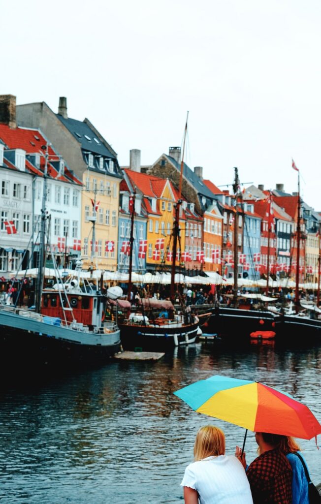 Friends sitting on the waterfont at Nyhavn in Copenhagen