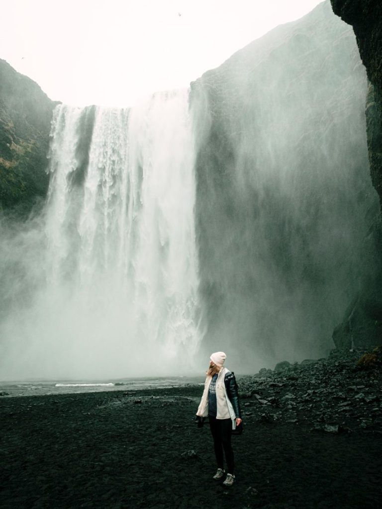 an image of a person staring at the skogafoss waterfall in iceland