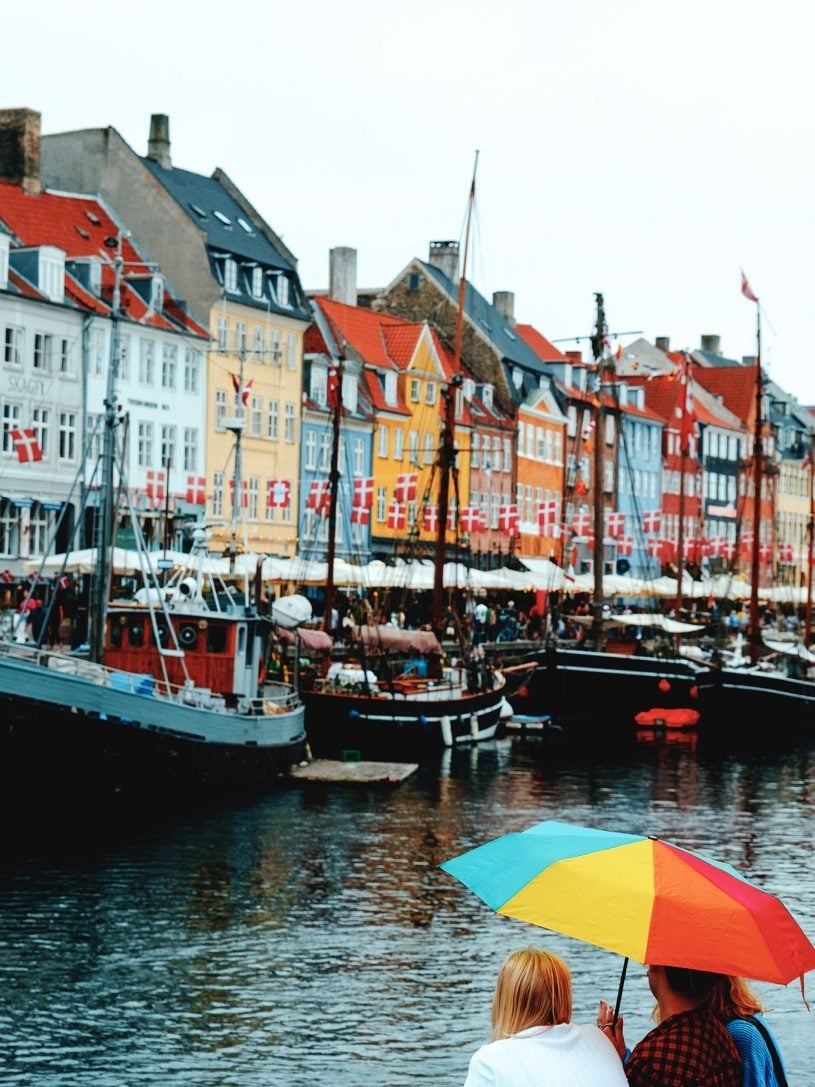 Friends sitting on the waterfont at Nyhavn in Copenhagen