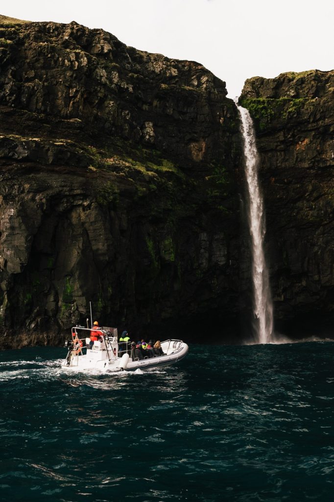 Taking a boat tour in the Faroe Islands and approaching a waterfall